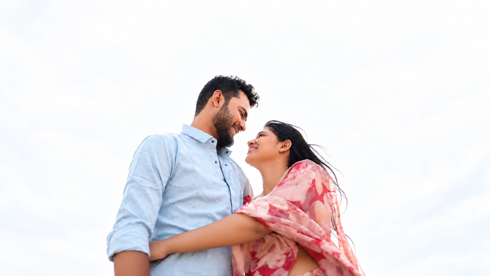 Couple smiling together beneath a bright sky